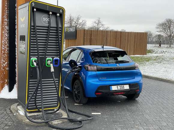 A blue car is plugged into an electric charging station.